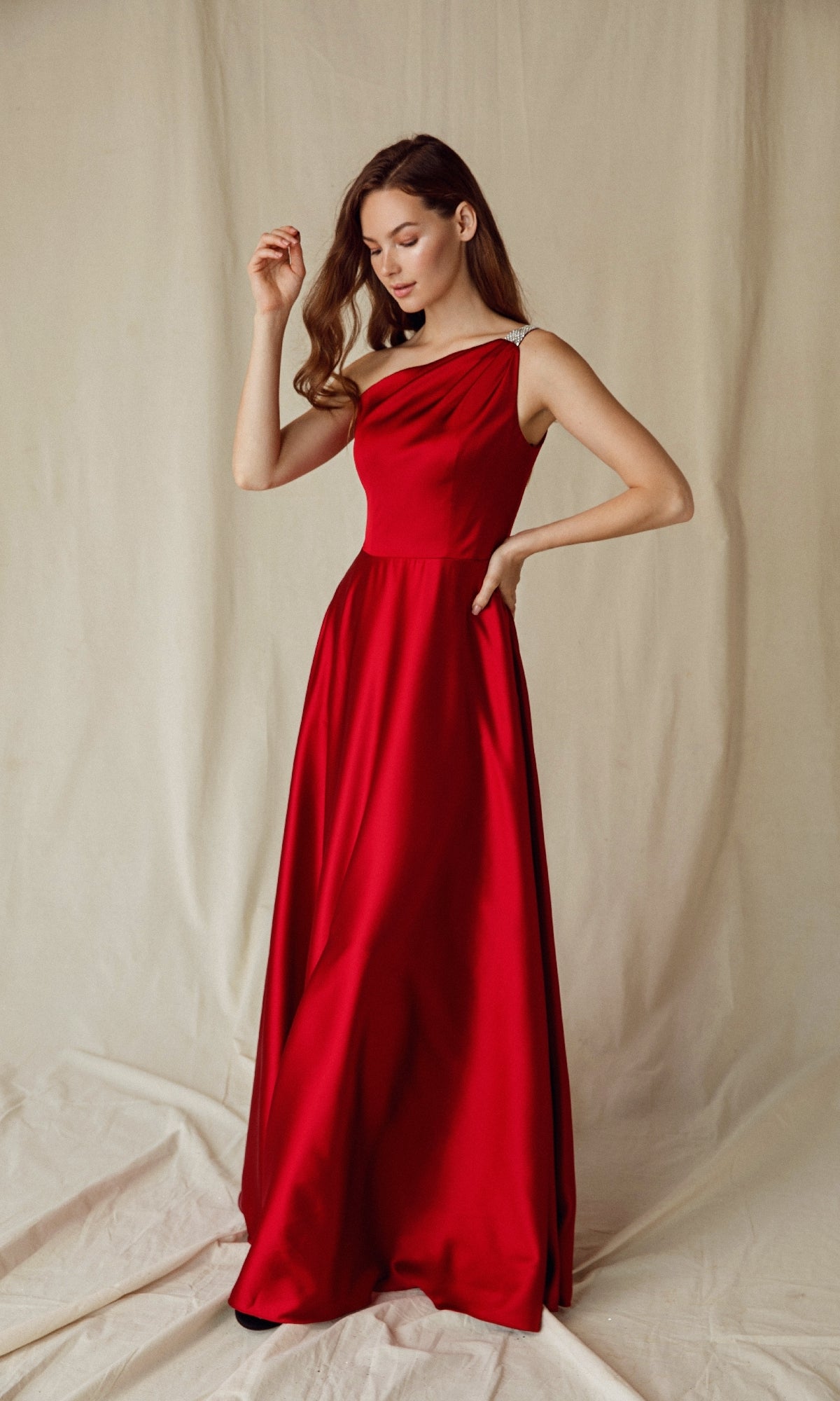 A woman poses against a neutral backdrop wearing the Eureka 9025: a one-shoulder, floor-length satin formal dress.